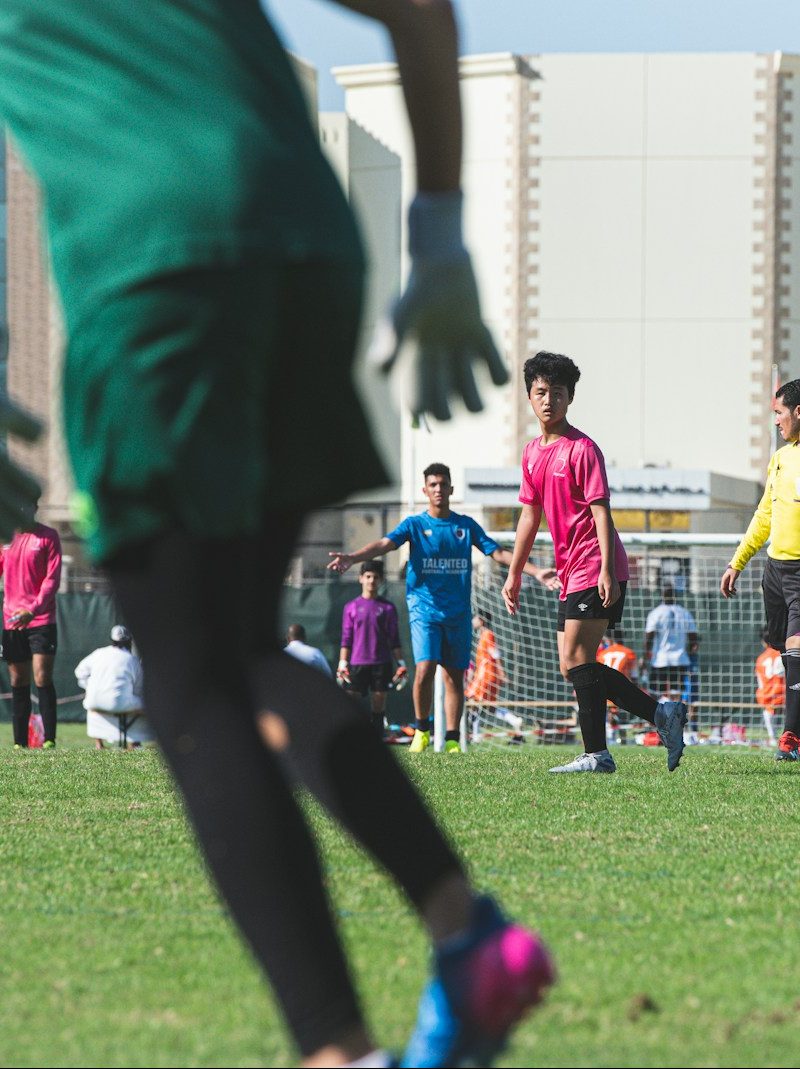people playing soccer on green grass field during daytime